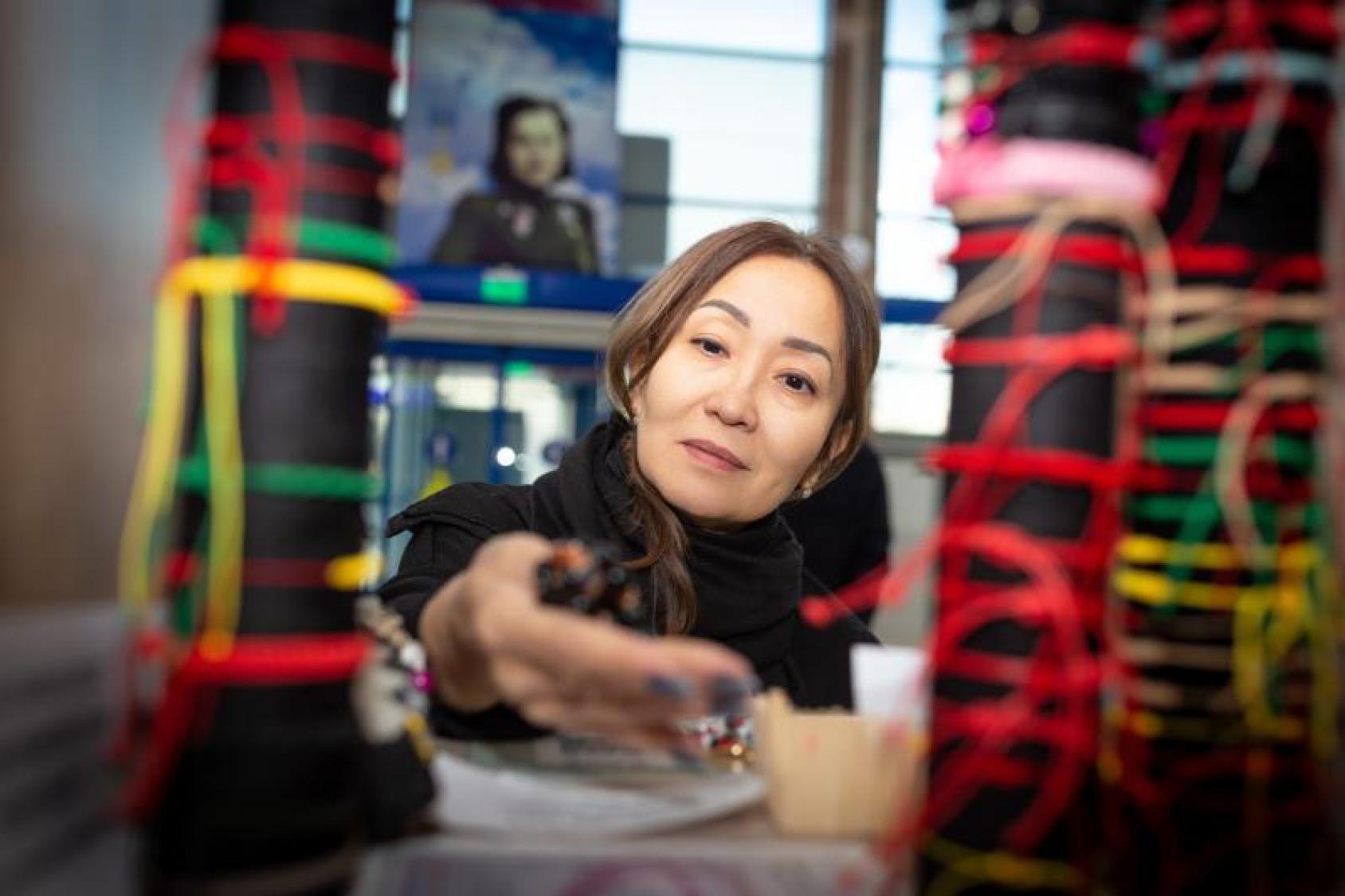 Woman in a blackshirt holding threads in red and green