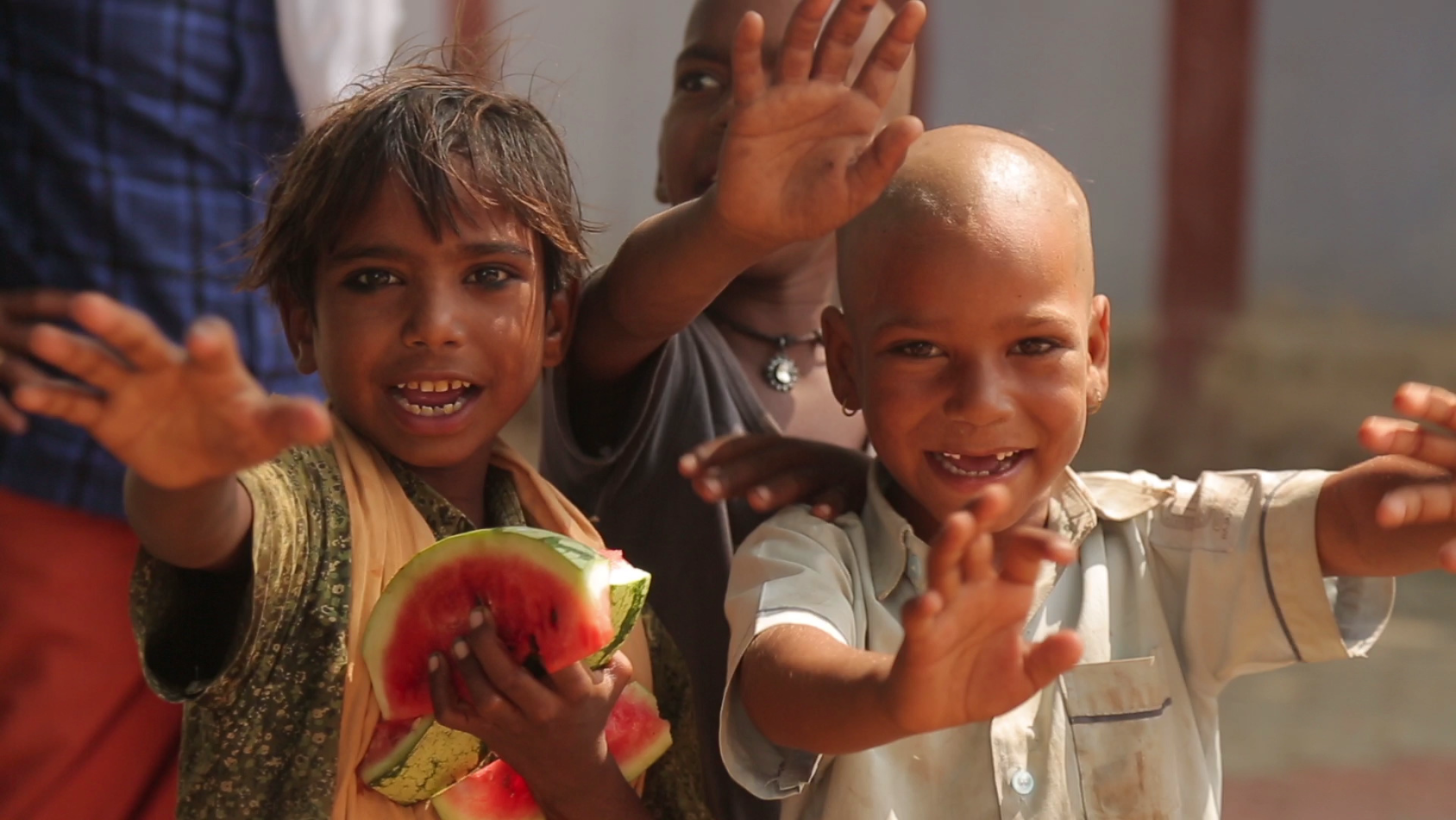 Kids throw their hands in the air and towards the camera while smiling.