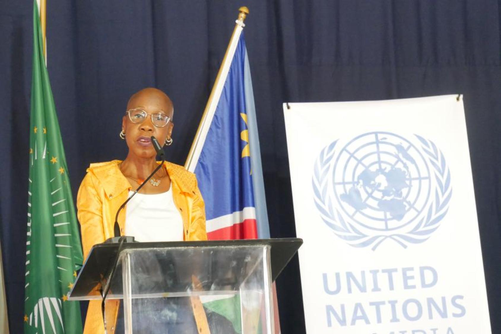 A woman in a yellow dress standing at a podium