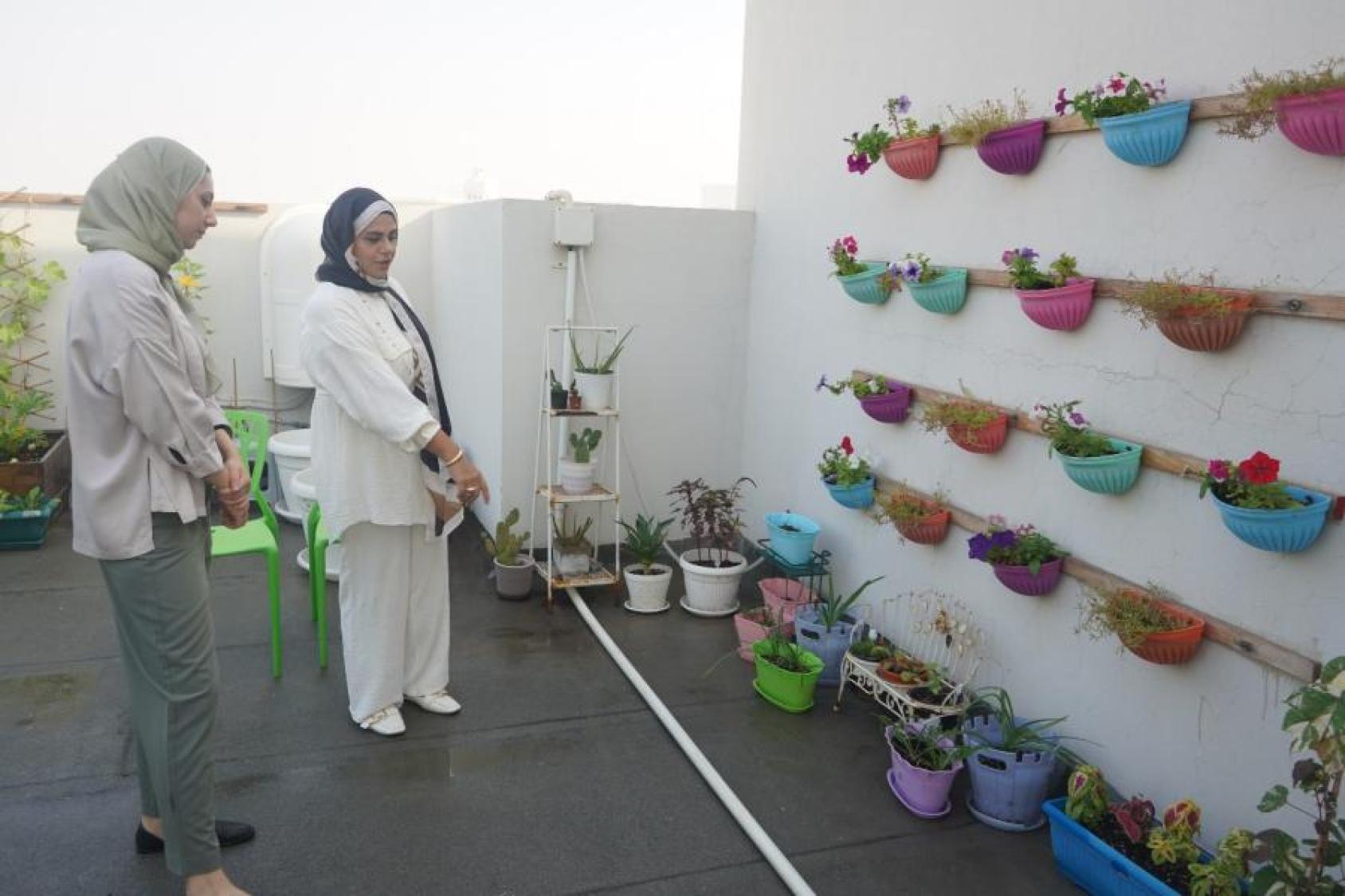 Two women look at a garden wall