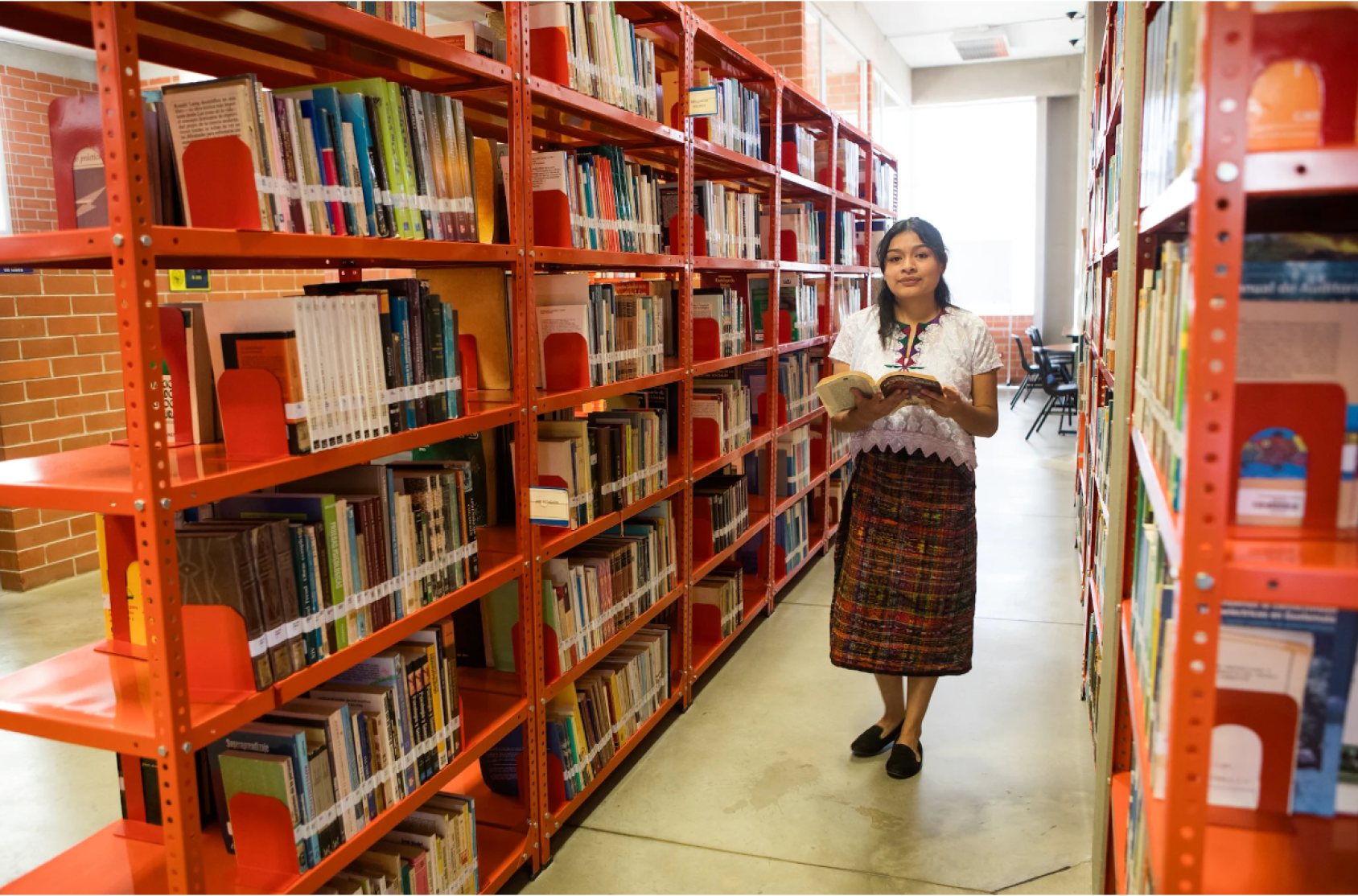 A woman in the middle of a library reading a book
