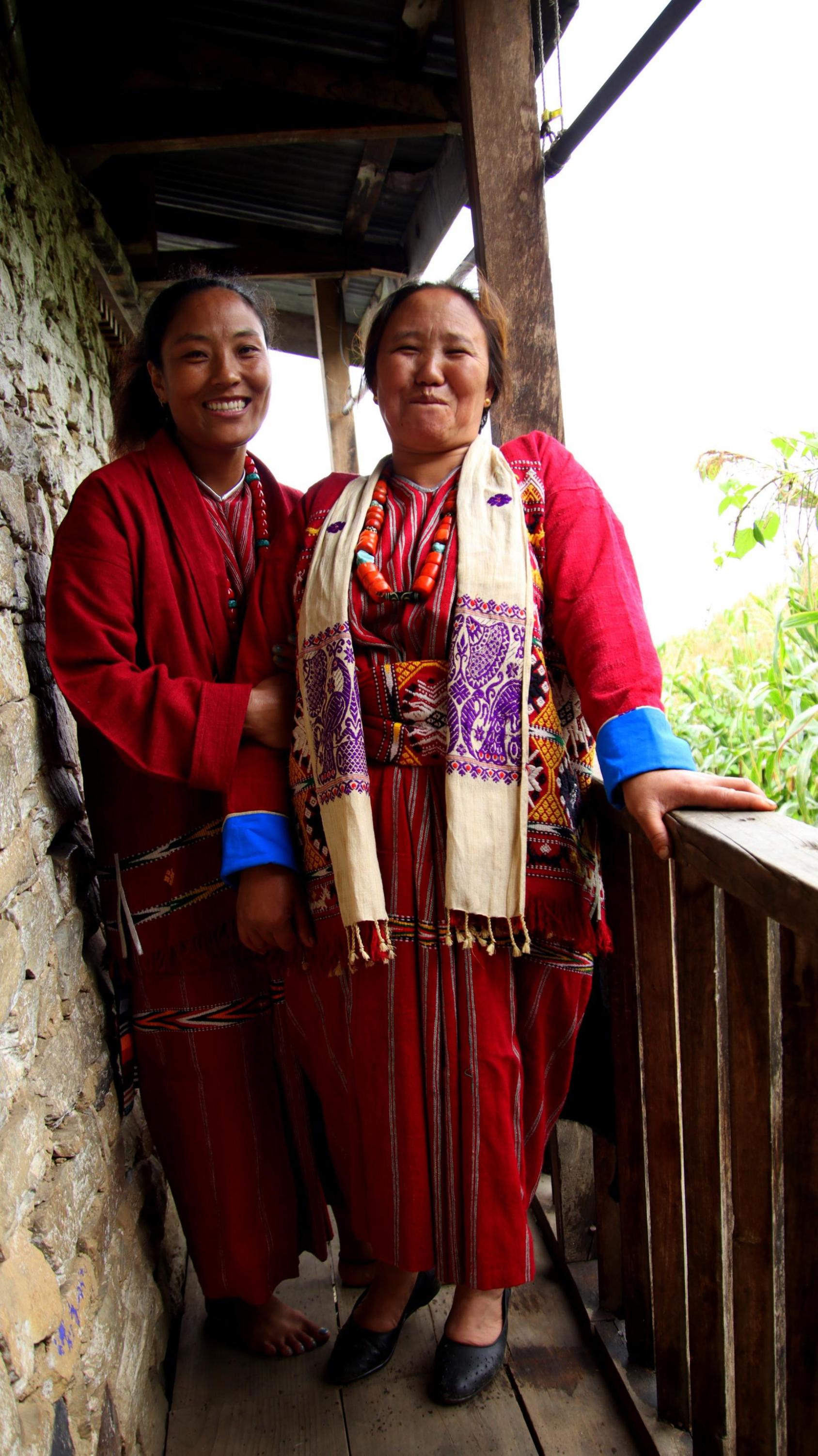 Two women are standing wearing colorful attire.