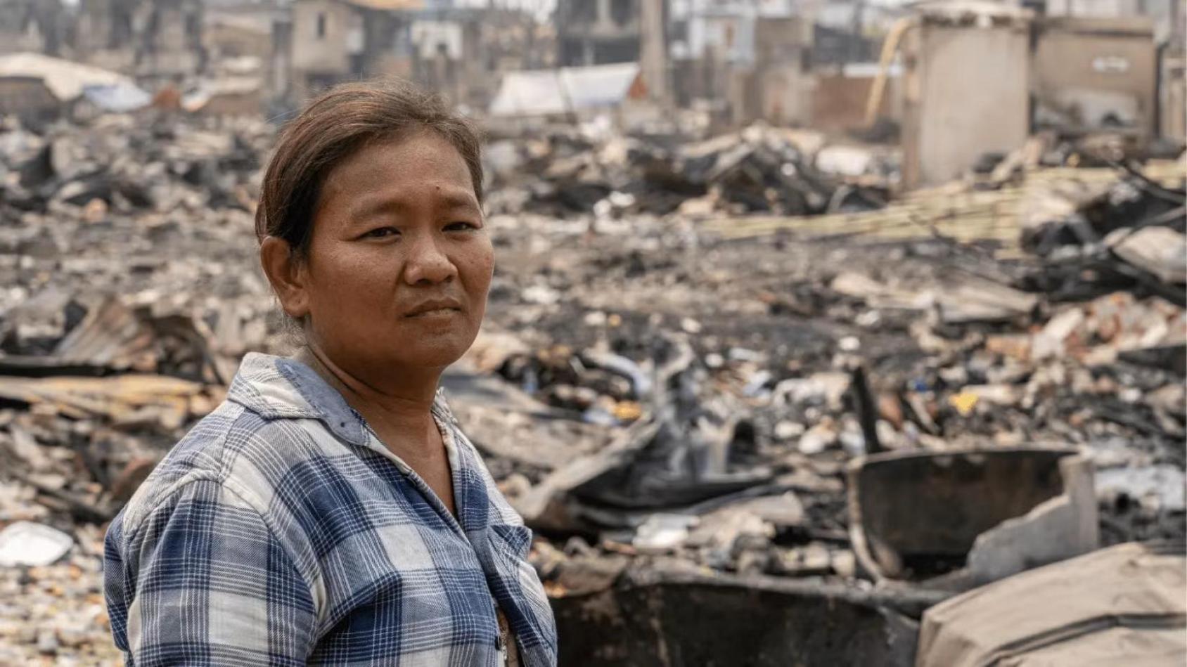 A woman stands amidst the rubble and debris at the site of what was once her home in Mandalay.