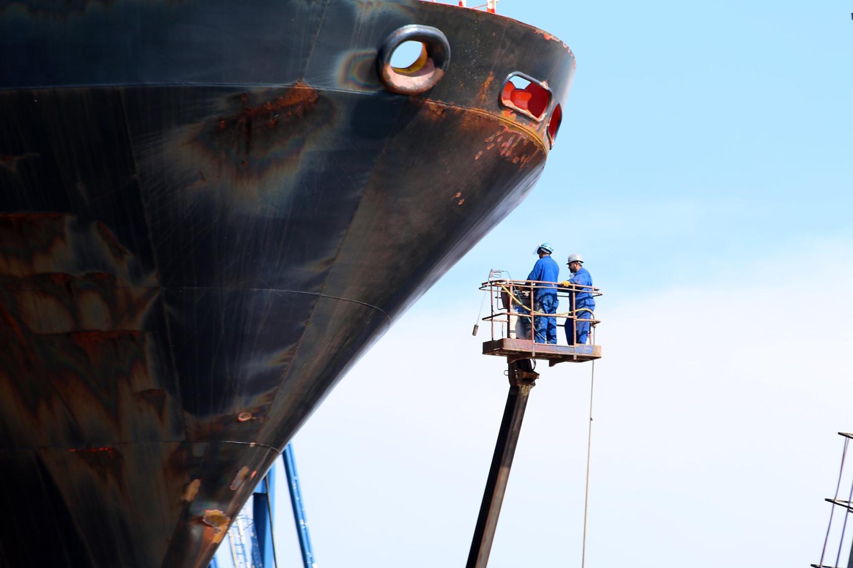 Two workers in front of a container ship