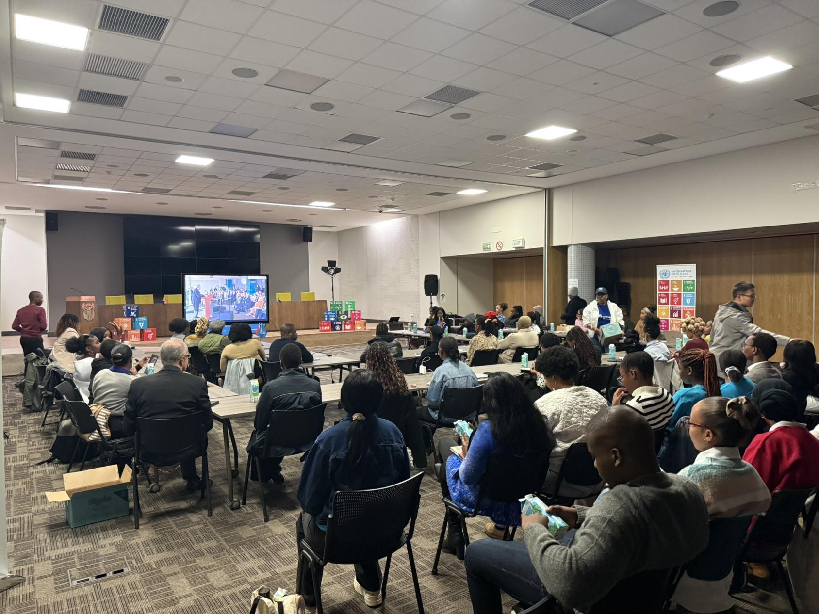 A group of young people seated in a room looking at a screen