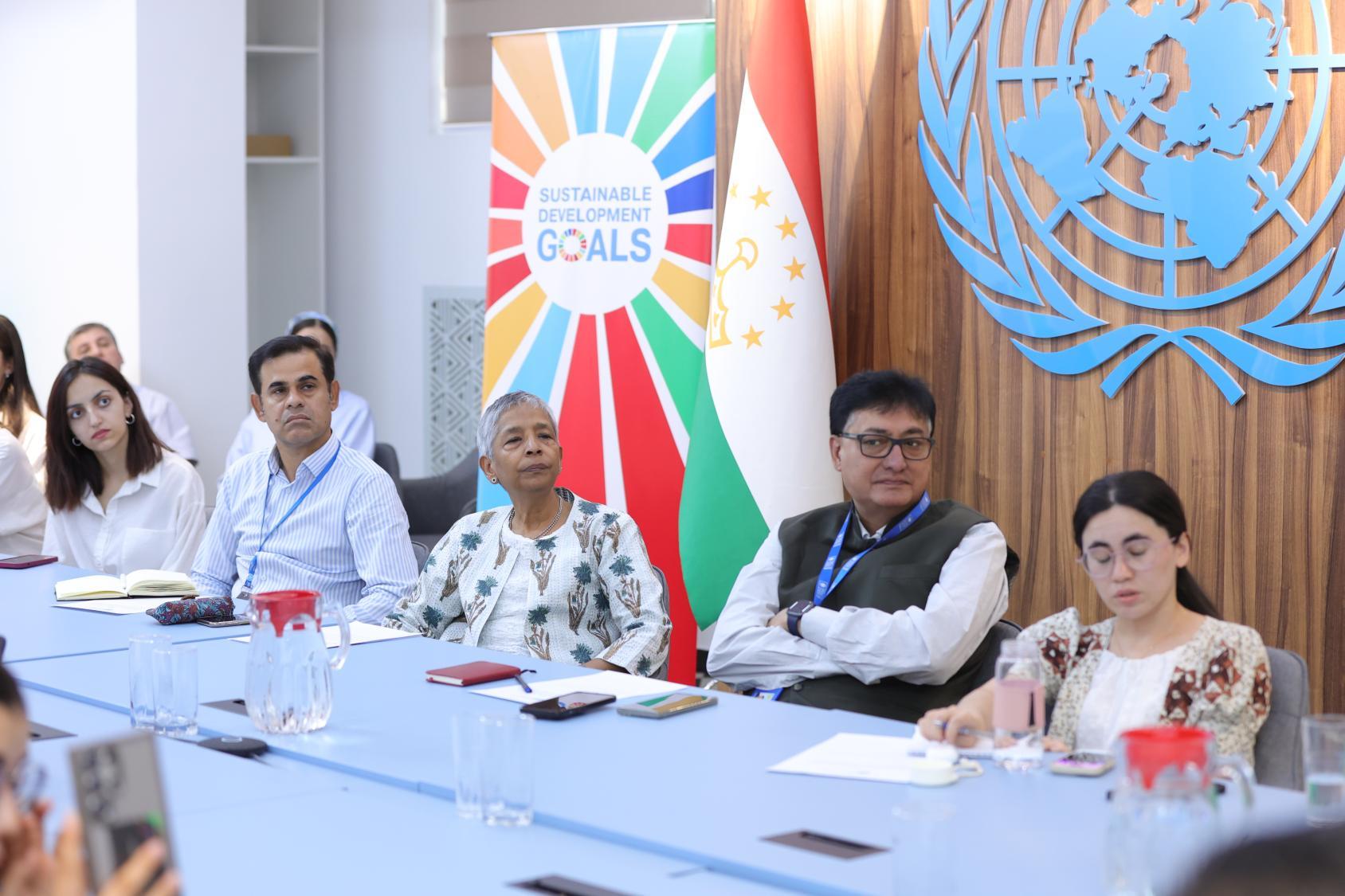 A group of peopleis listening seated in front of a background with the UN logos
