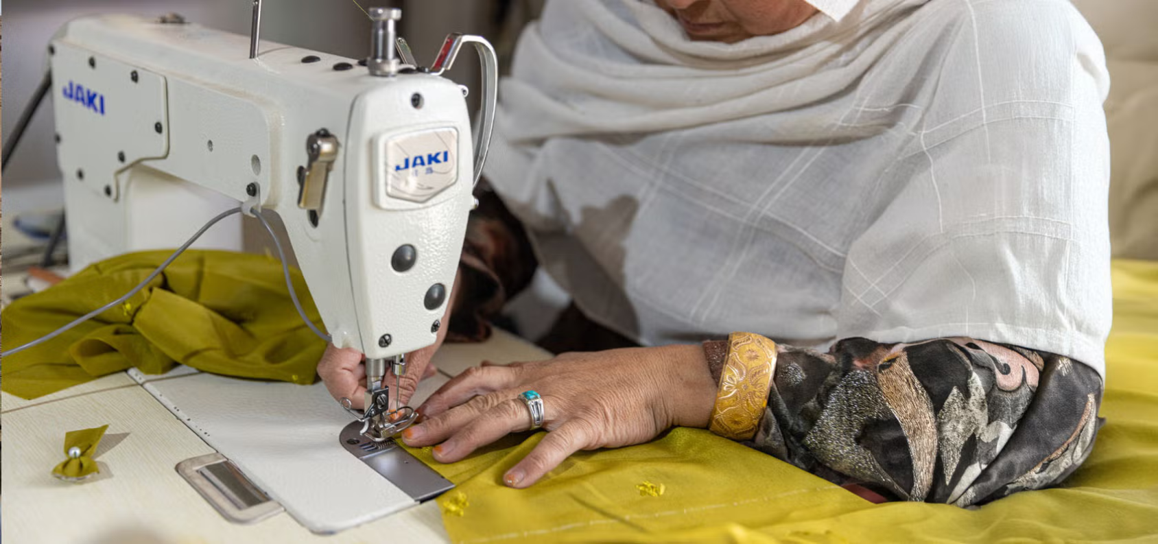 Hands of a woman moving cloth through a tailoring machine