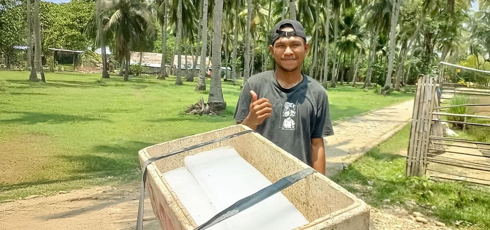 A man shows his cart of ice blocks and gives a thumbs-up