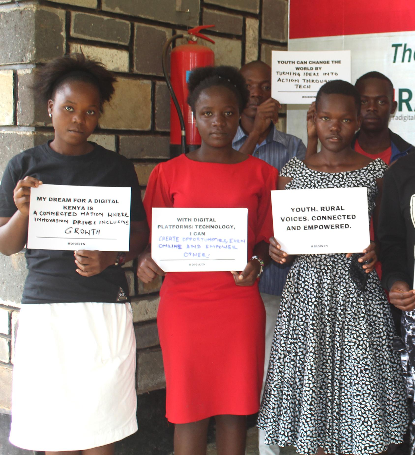Three young women in black, white and red clothes, holding up placards with their hopes for our digital future