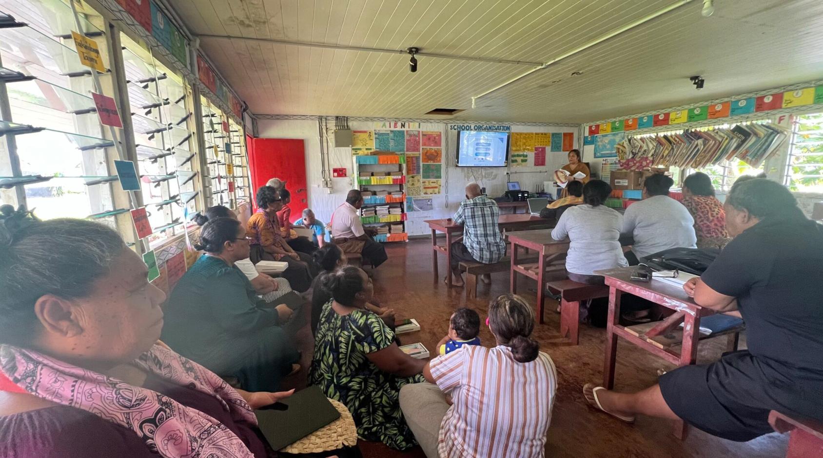 A classroom in a school with teachers and students watching a screen.