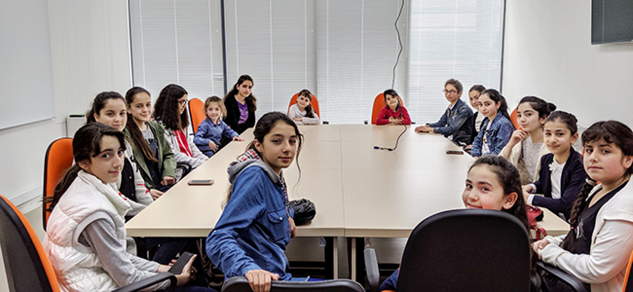 Un grupo de niñas se sientan alrededor de la mesa de una sala de conferencias