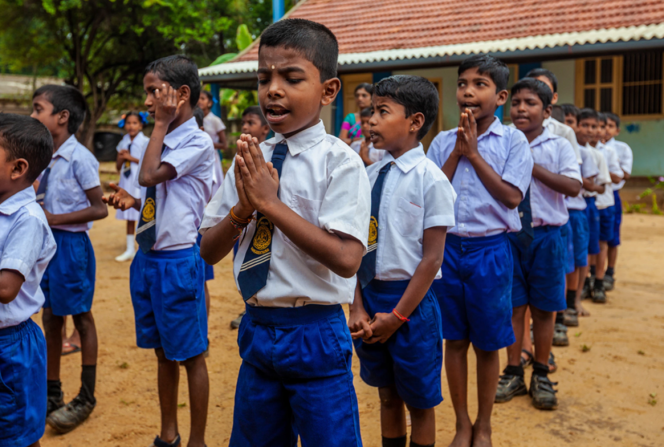 Photo shows boys lined up outside the school. Caption: Children start the day at school in Kankesanthurai; most of the children are from families who have recently resettled to the area after years of displacement.