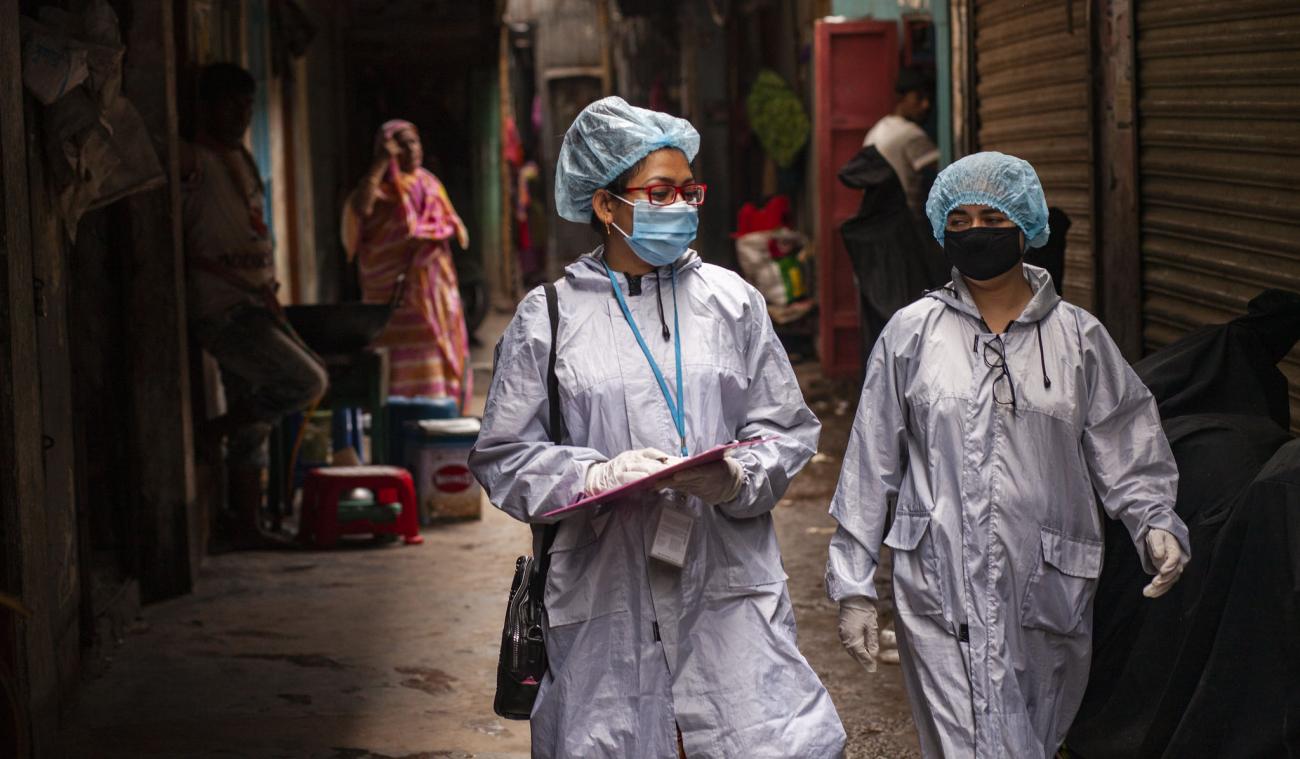 Dos trabajadores de desarrollo miran su lista de verificación durante una campaña de sensibilización en Dhaka en el marco del proyecto LIUPC del PNUD en Bangladesh.