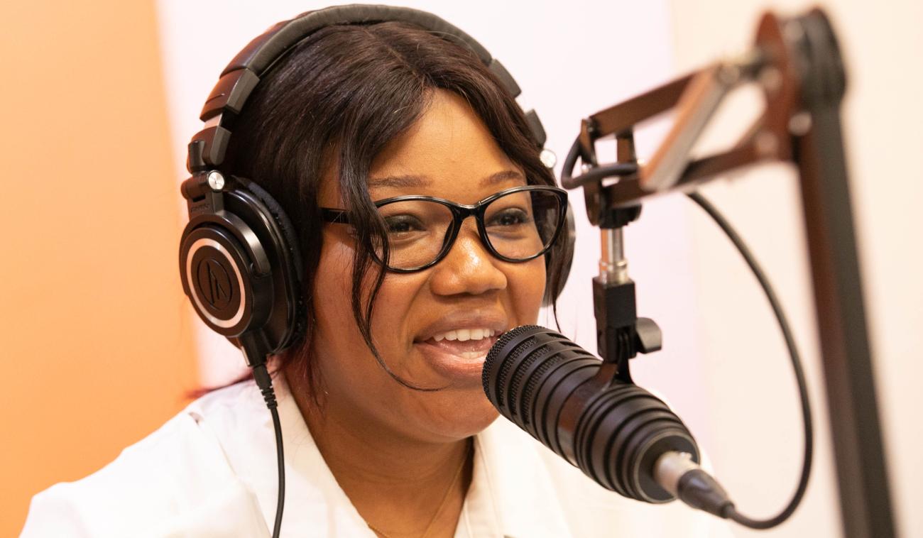 Young person wearing headphones speaks into a radio station microphone.