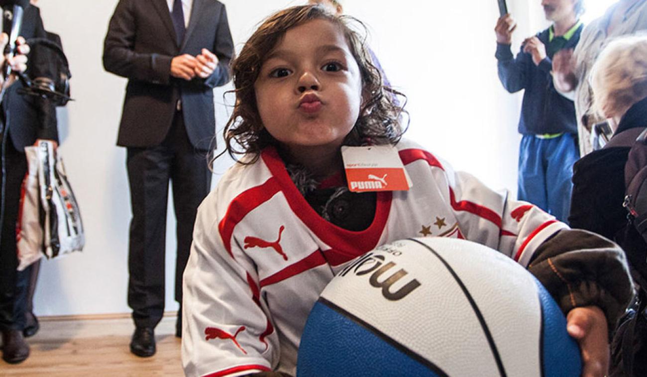A little boy holds a basketball and puckers his lips at the camera. 