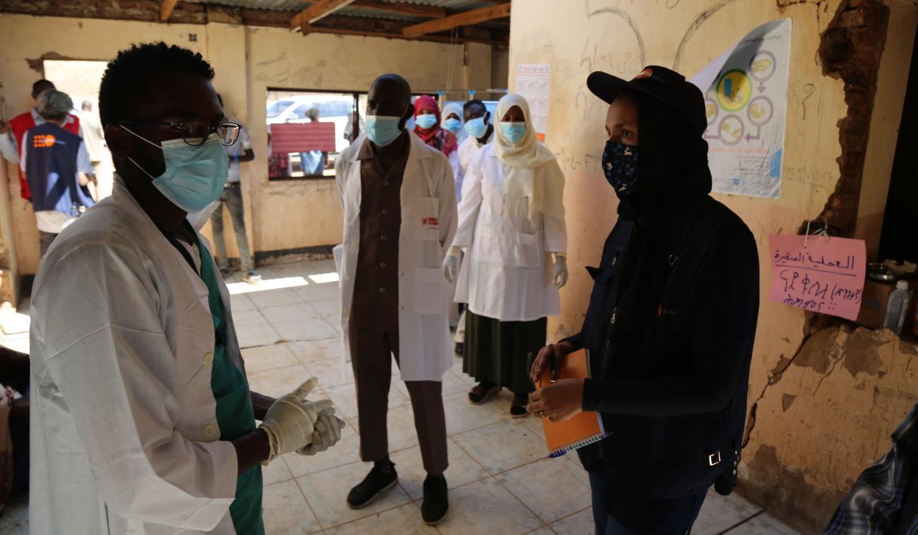 Medical personnel speak to UN staff at the camp medical facility as they wear PPE and social distance.