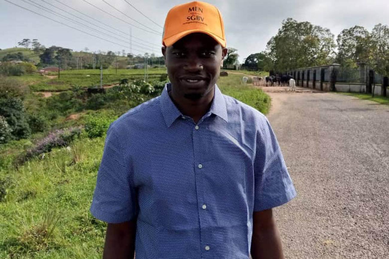 Clement smiles proudly wearing an orange cap that shows his support of fighting to end gender-based violence.