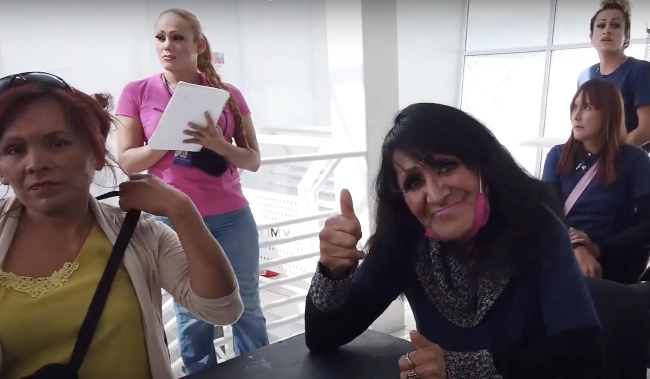 Varias mujeres transgénero se unen como parte del programa de la ONU. Una de ellas, en primer plano de la imagen, sonríe a la cámara levantando el pulgar afirmativamente.