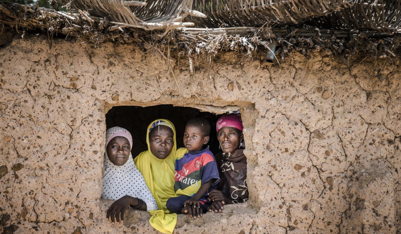 امرأتان مع طفلتين تظهران داخل إطار نافذة منزلهما في النيجر.