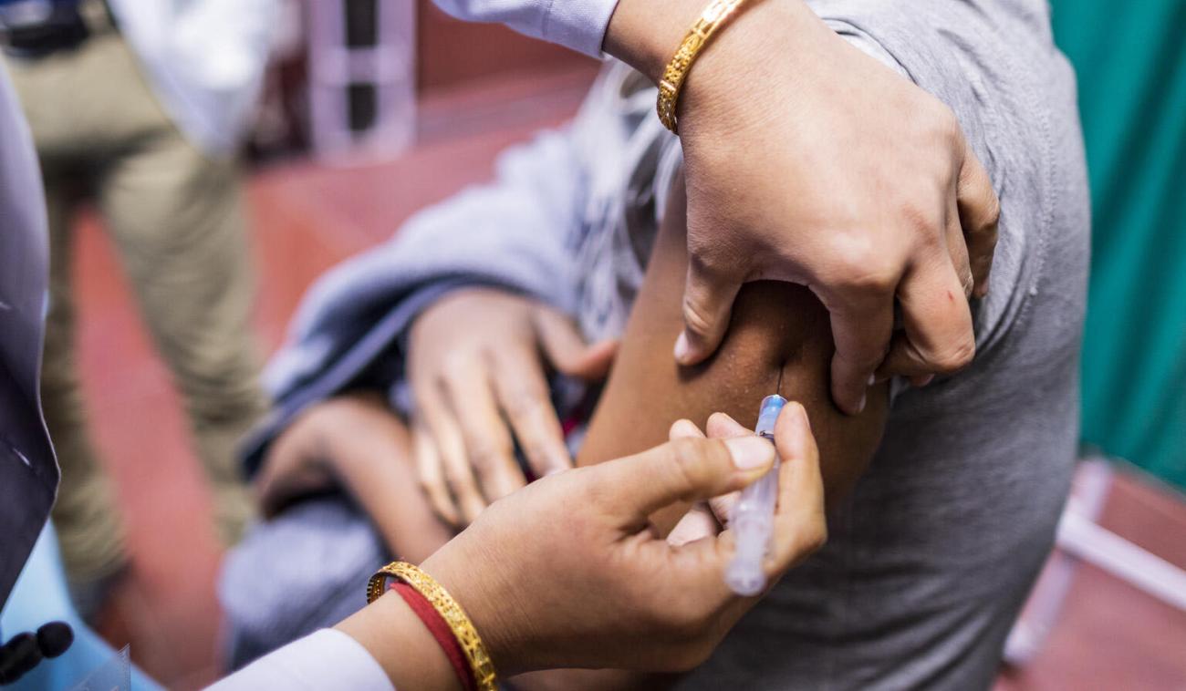 Un primer plano de un proveedor de atención médica inyecta la vacuna COVID-19 en el brazo de una persona.