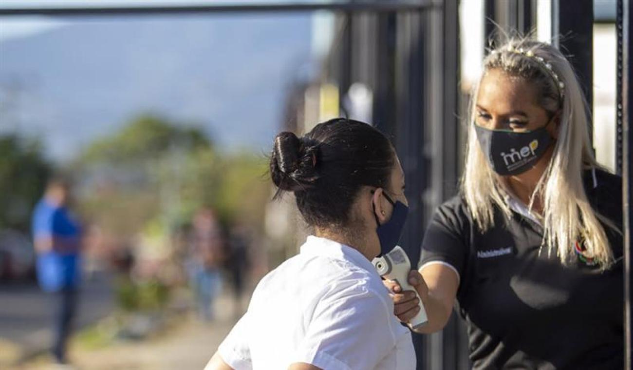 Une professeure contrôle la température d'une élève avant de la laisser entrer dans le bâtiment de l'école.