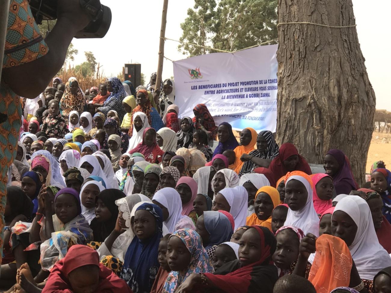 一大群人一起站在写有法语单词的白色大横幅前。