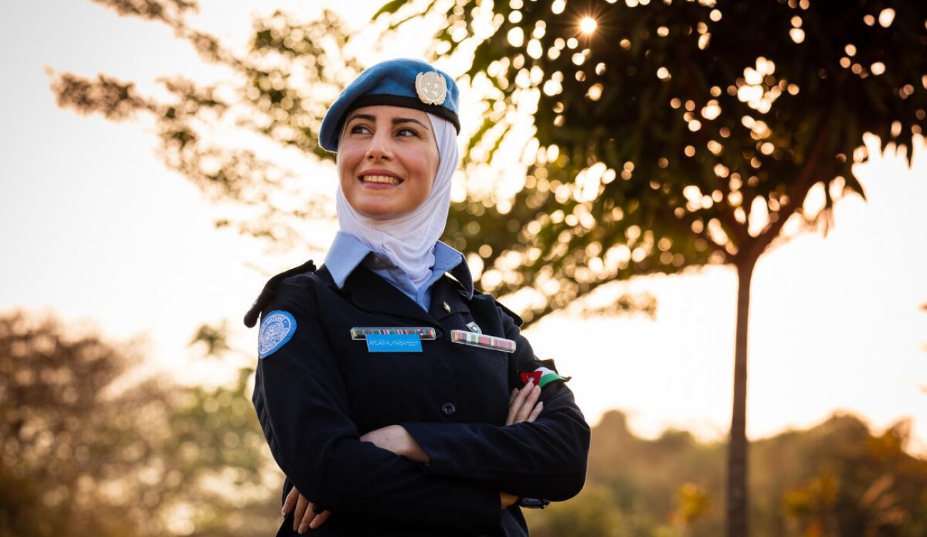 Le Capitaine Ahlam Al-Habahbeh, portant fièrement son uniforme, pose devant l'objectif, les bras croisés, non loin d'un arbre.