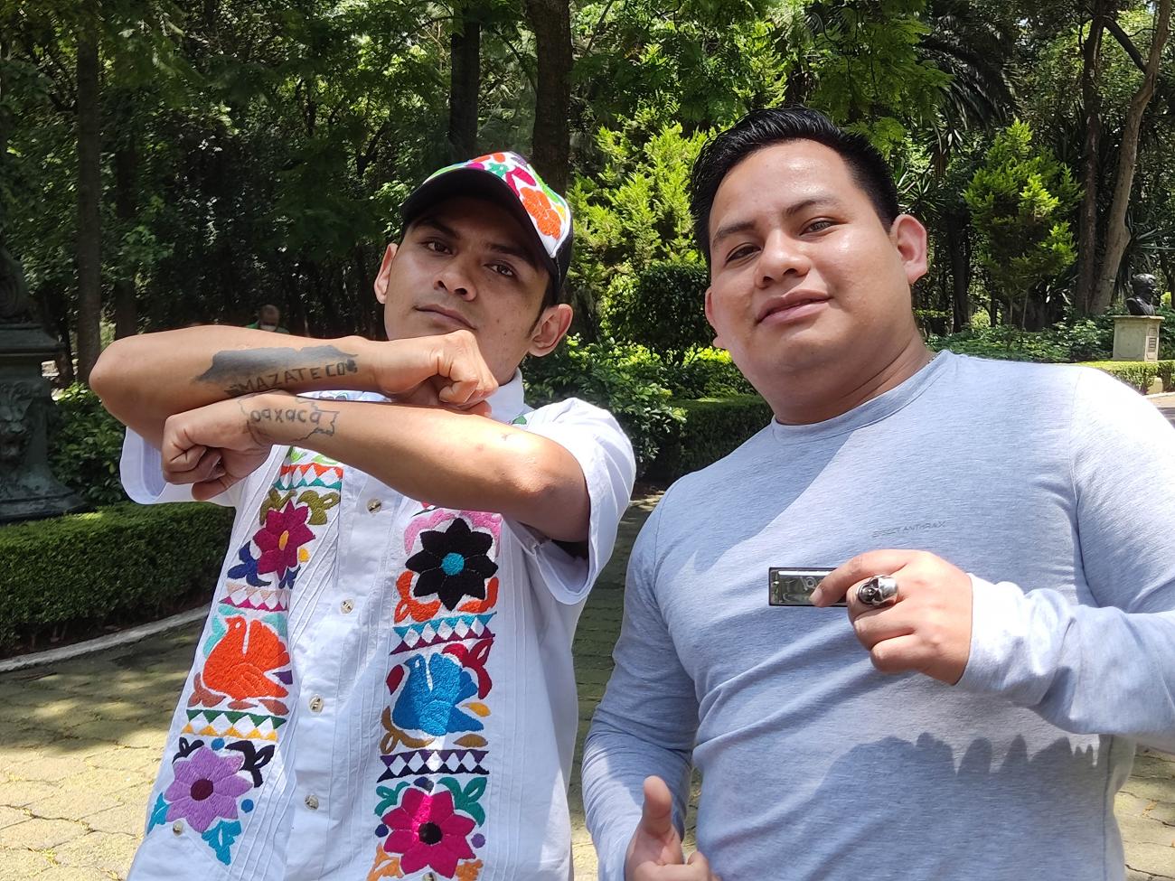 Dos hombres permanecen juntos cerca de una zona boscosa.