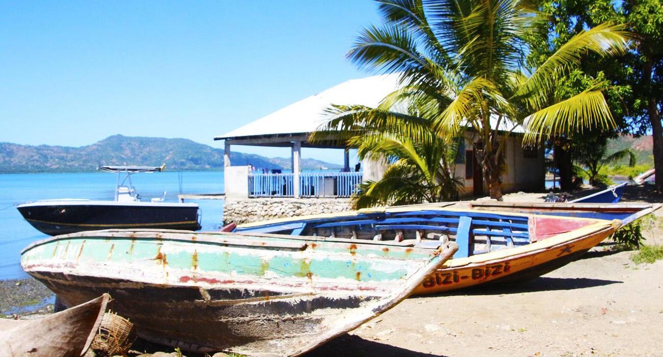 Barcos de madera abandonados en una playa junto a un negocio.