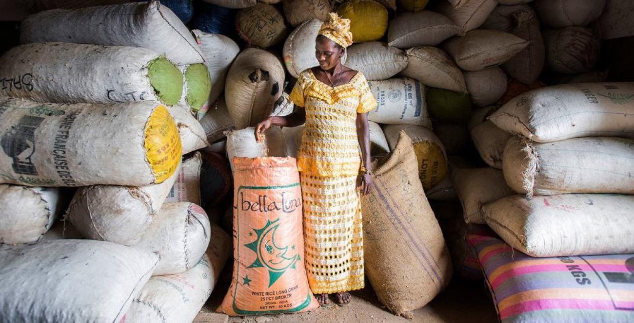 Una agricultora se encuentra junto a muchos sacos de cultivo.