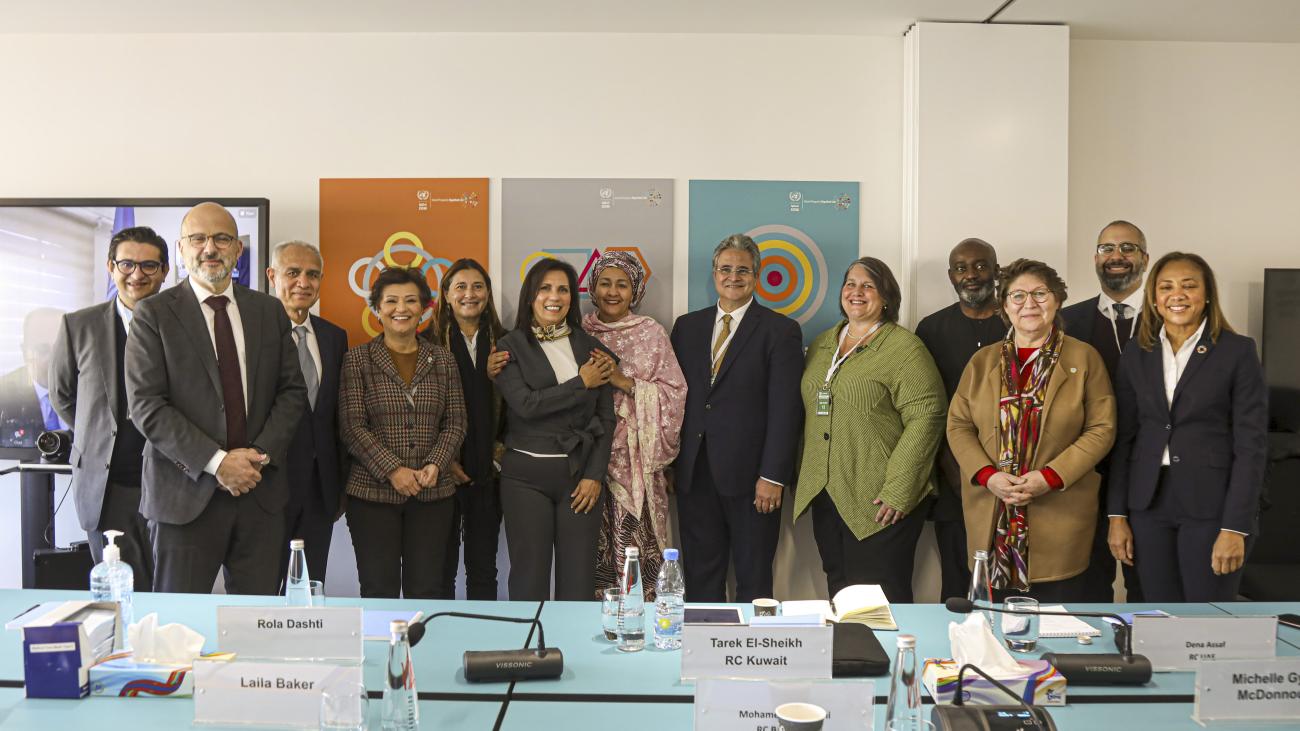 Un groupe de représentants de l'ONU se tiennent debout, côte à côte, dans une salle de réunion, et sourient en se faisant photographier.