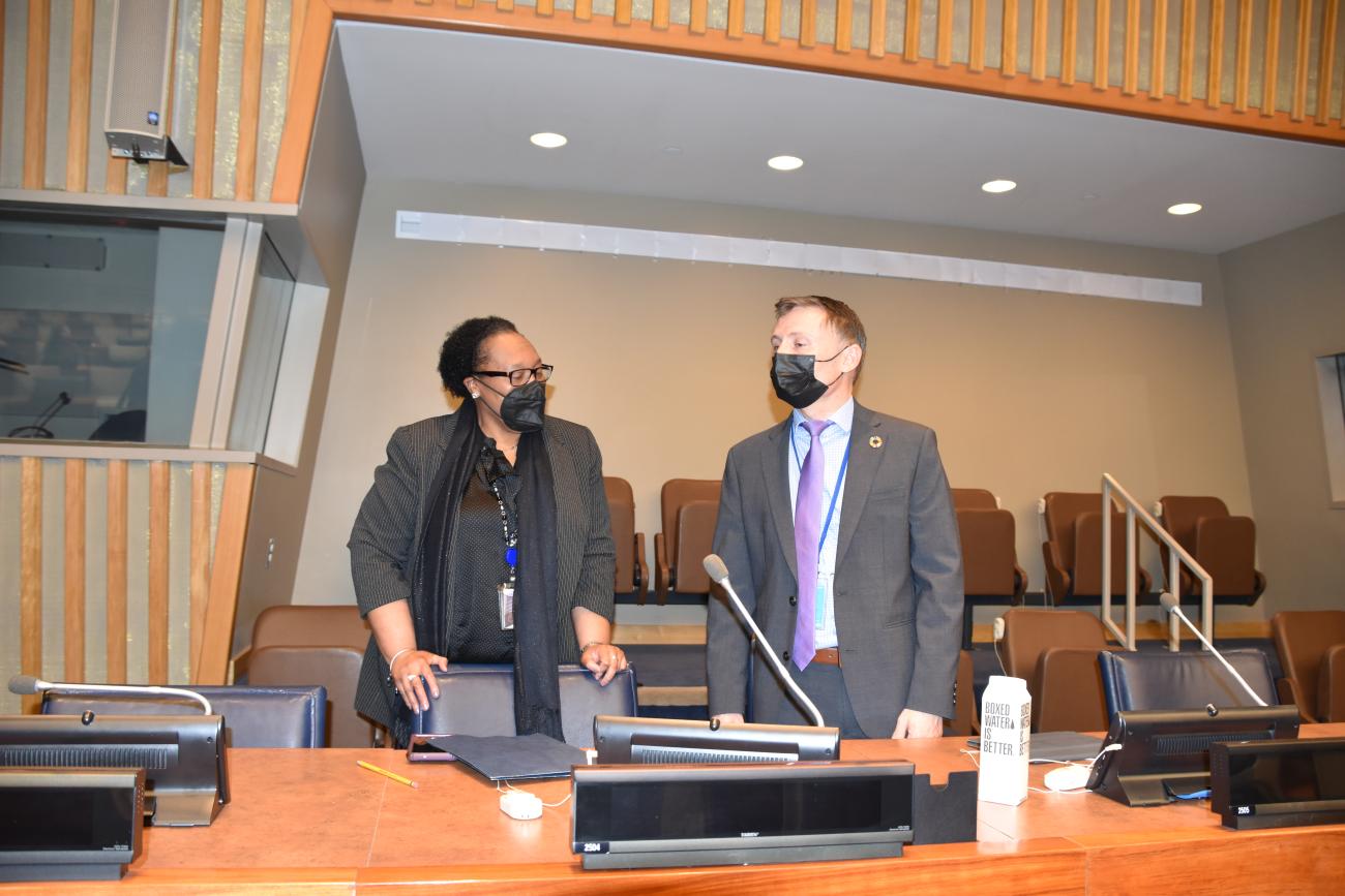 一个女人和一个男人在一个房间里交谈，两人都带着口罩。