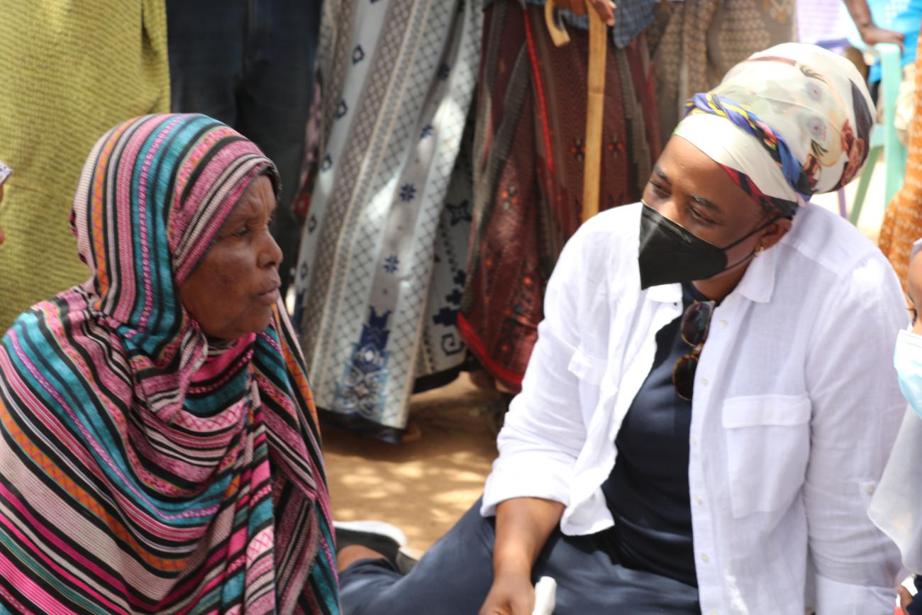 Two women are talking next to a hut.