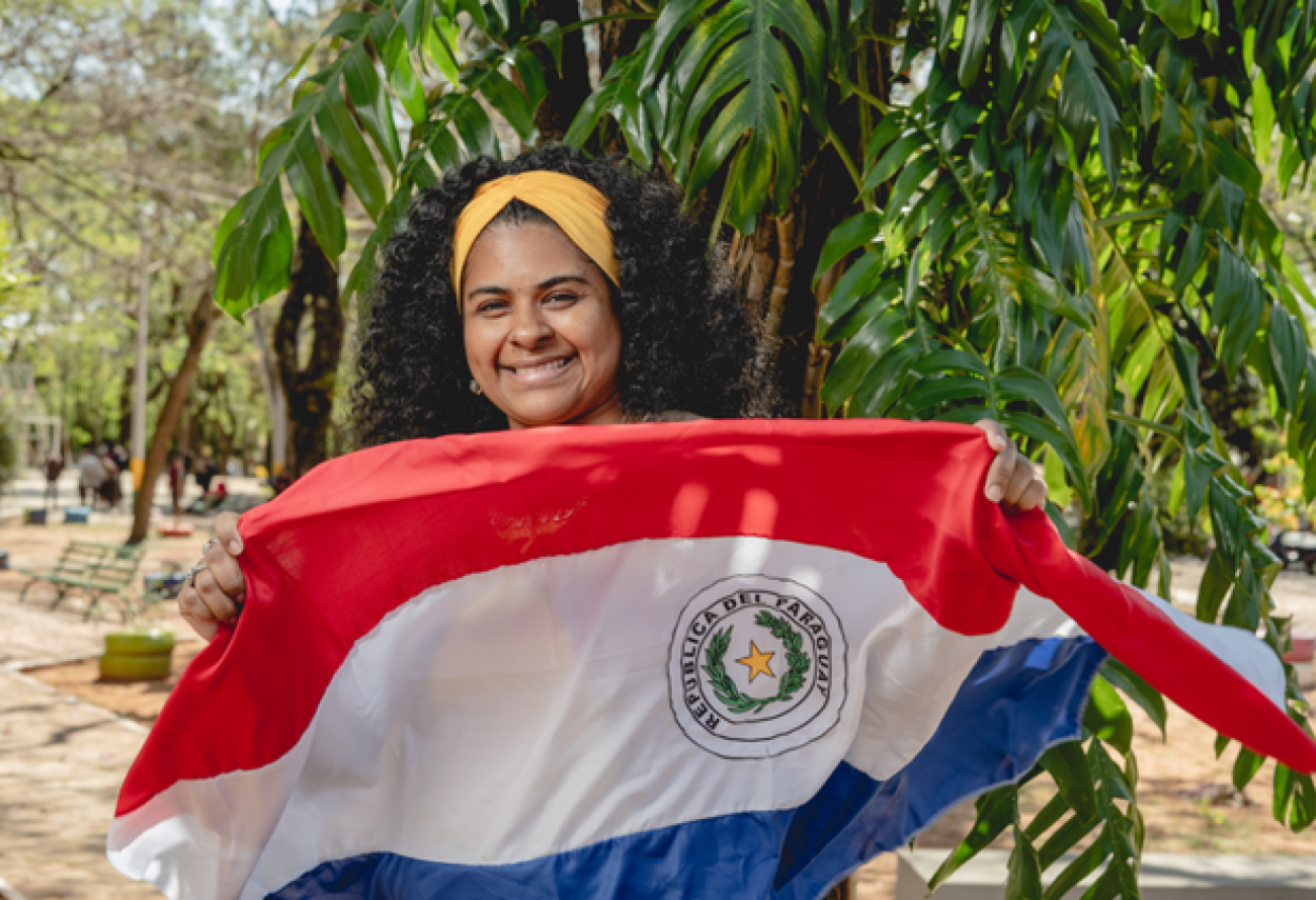 Una joven sonriente con una bandera de Paraguay entre las manos.