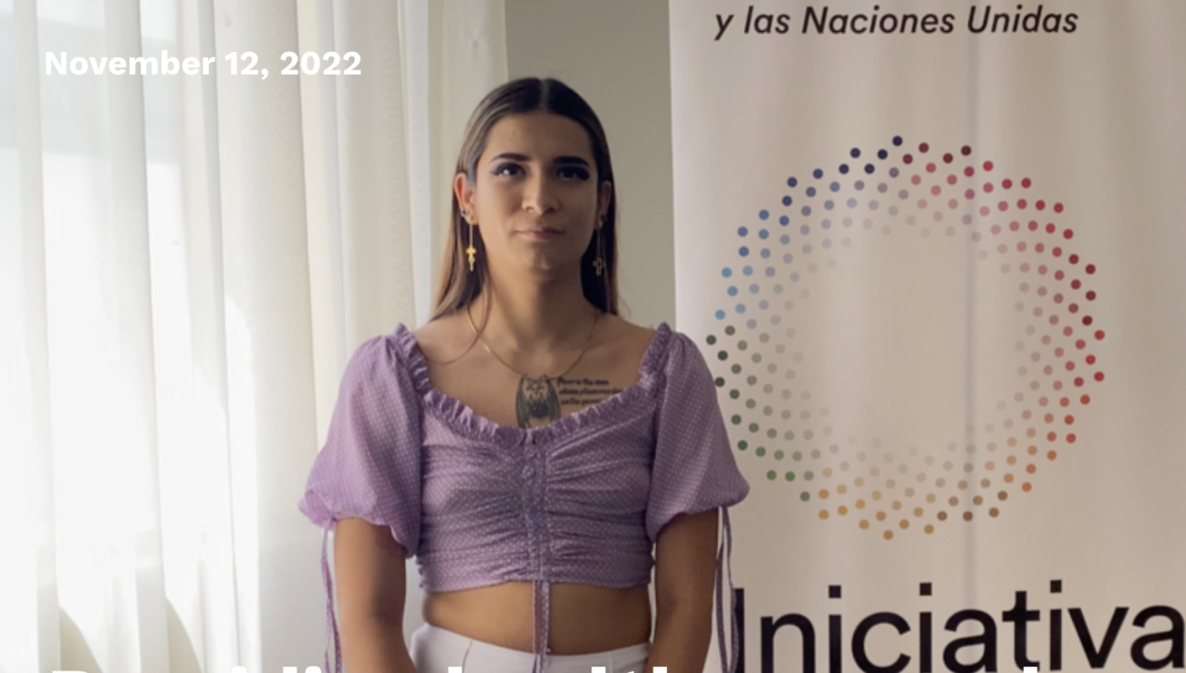 Person in a purple dress standing in front of a white background with the Spotlight Initiative logo.
