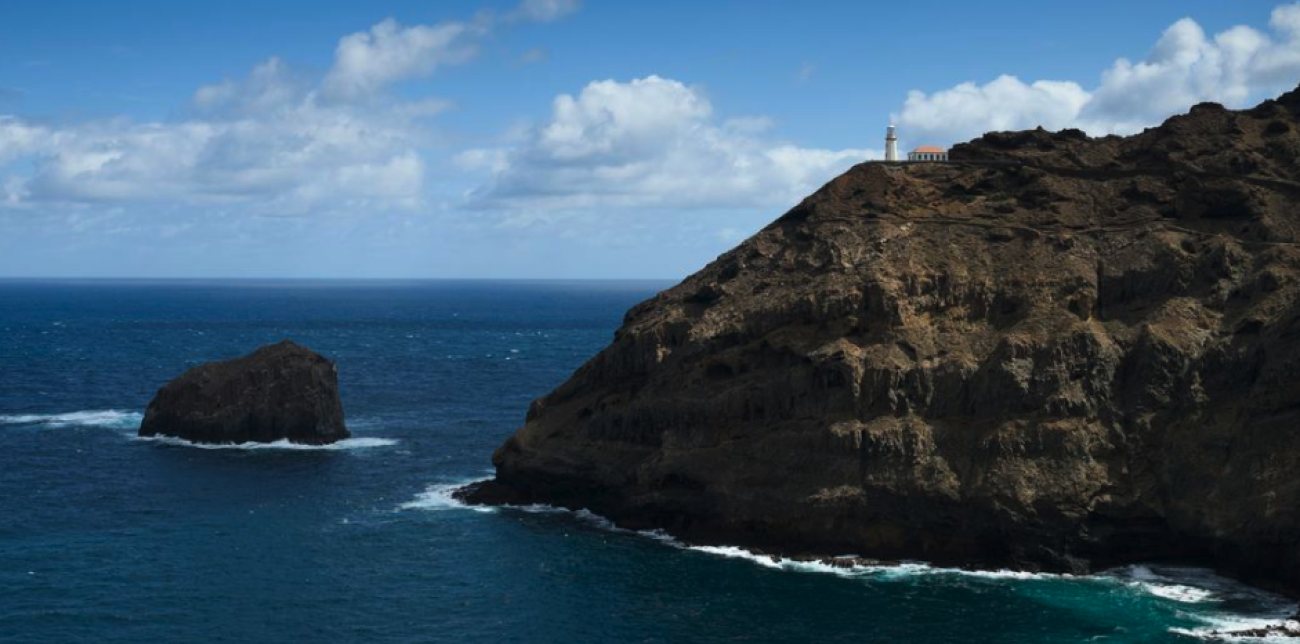 A view of a coastline in an archipelago, with bright blue water in front of jagged cliffs