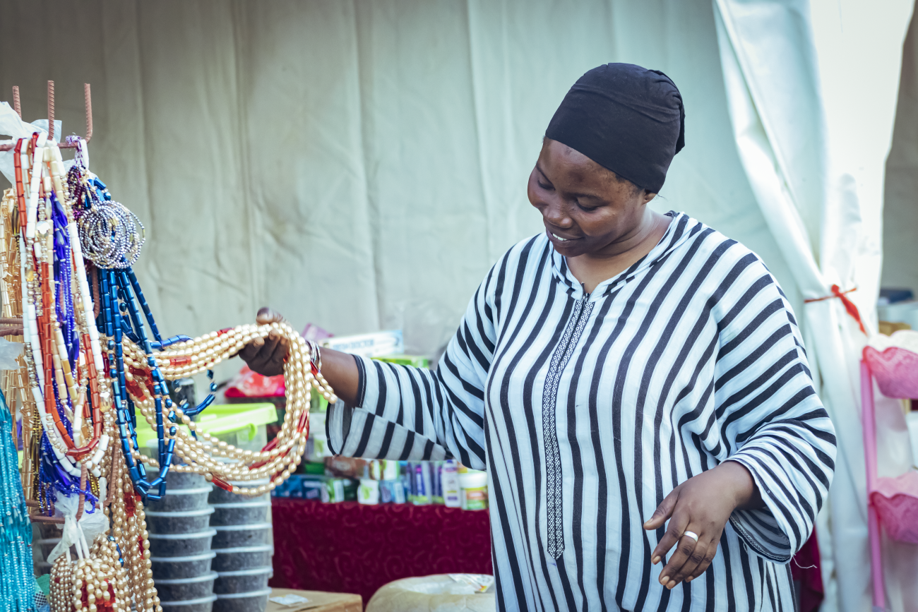 A woman in a black headscarf and striped dress runs her fingers through some jewellery