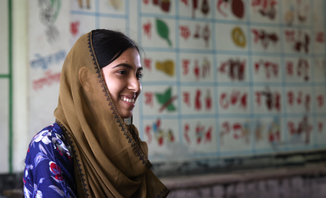 woman in brown head scarf smiles side on the camera