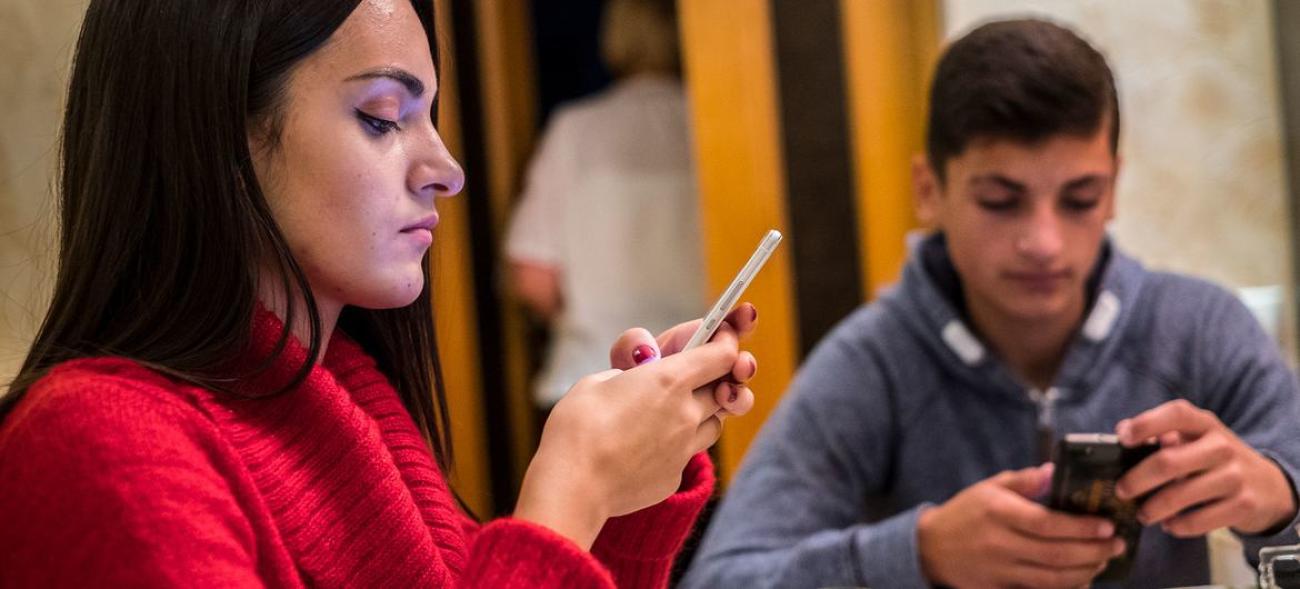 A man and woman stare at their phones