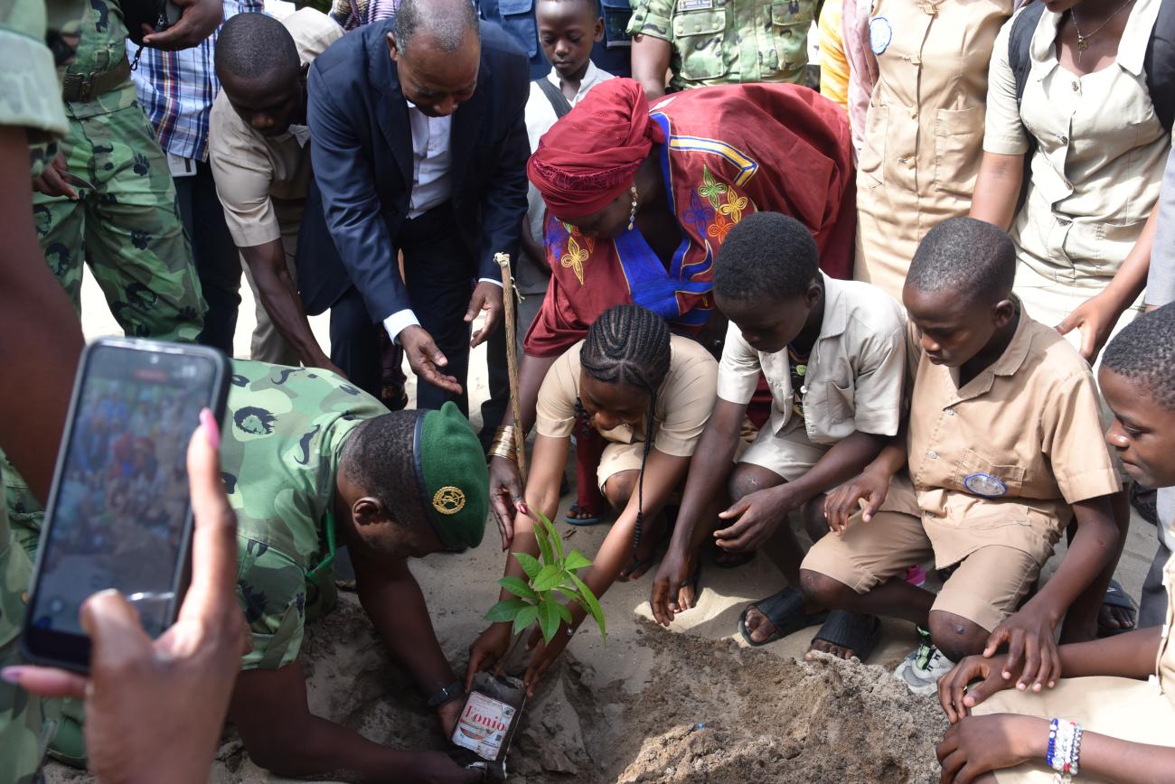 Un groupe de personnes plantant un arbre avec une jeune fille au milieu.