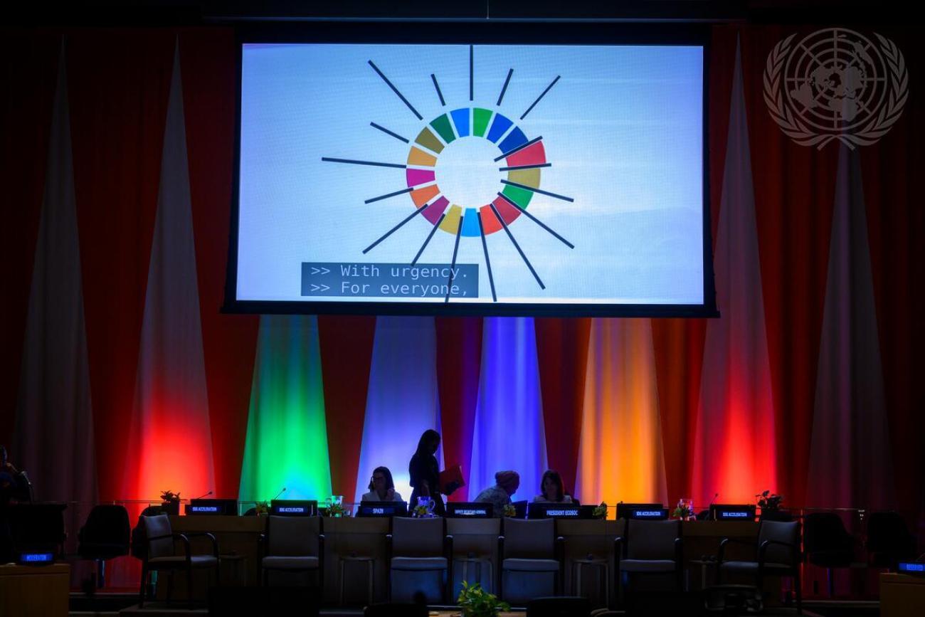 A silhouette of the SDG colours lighting up a screen at the UN ECOSOC Hall.