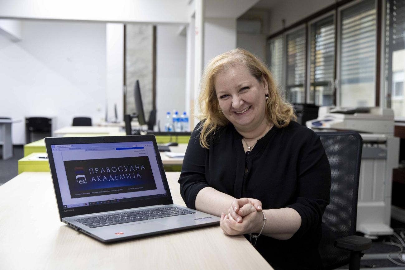 A woman seated at a computer looking at the camera