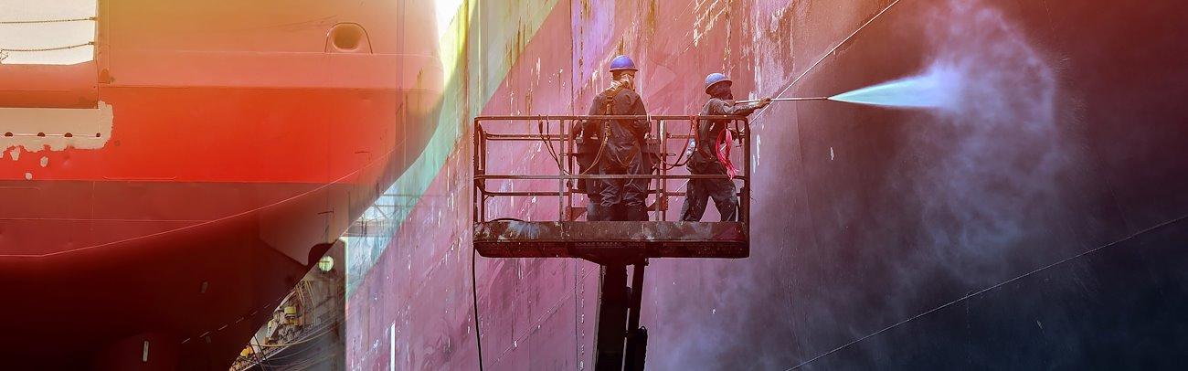 Two workers cleaning a container ship