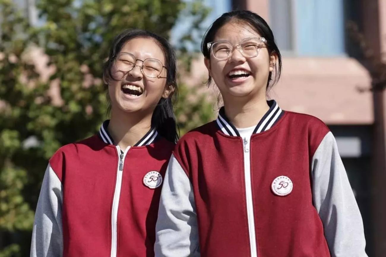 Две девочки в школьной форме весело смеются