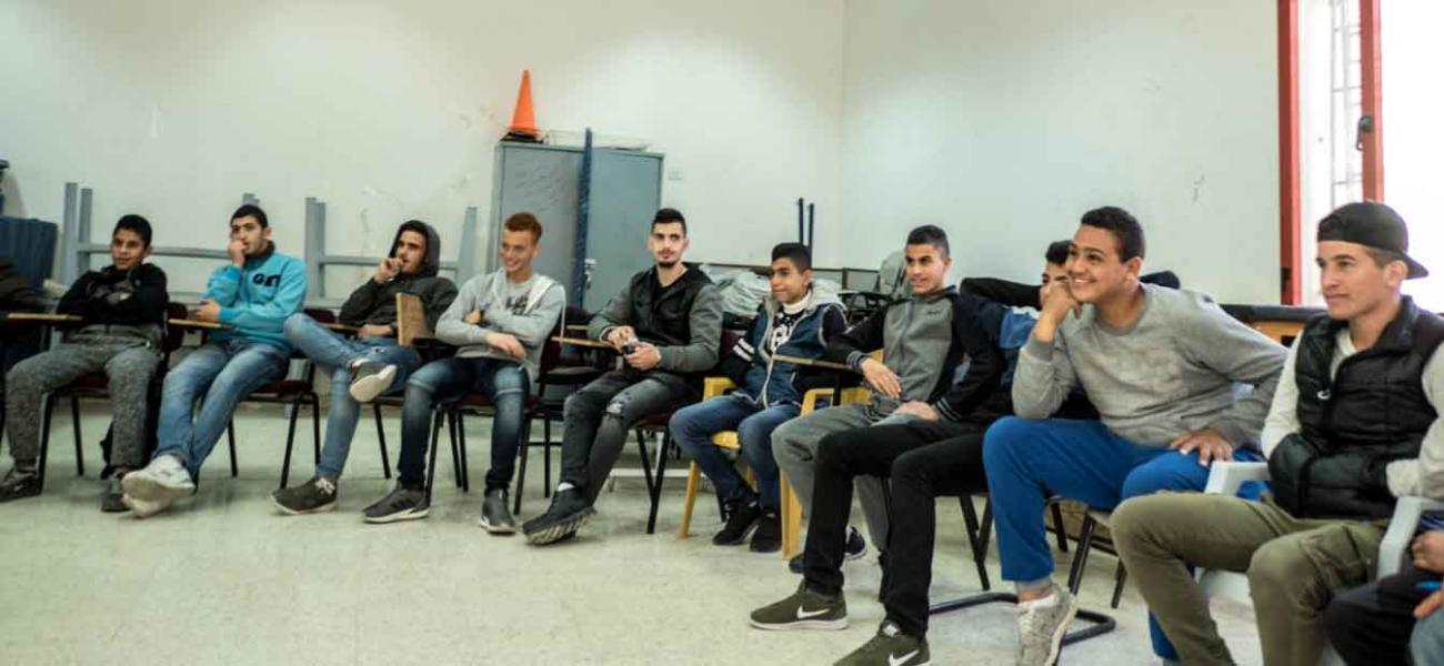 عدد من الشبان يجلسون في قاعة كبيرة.