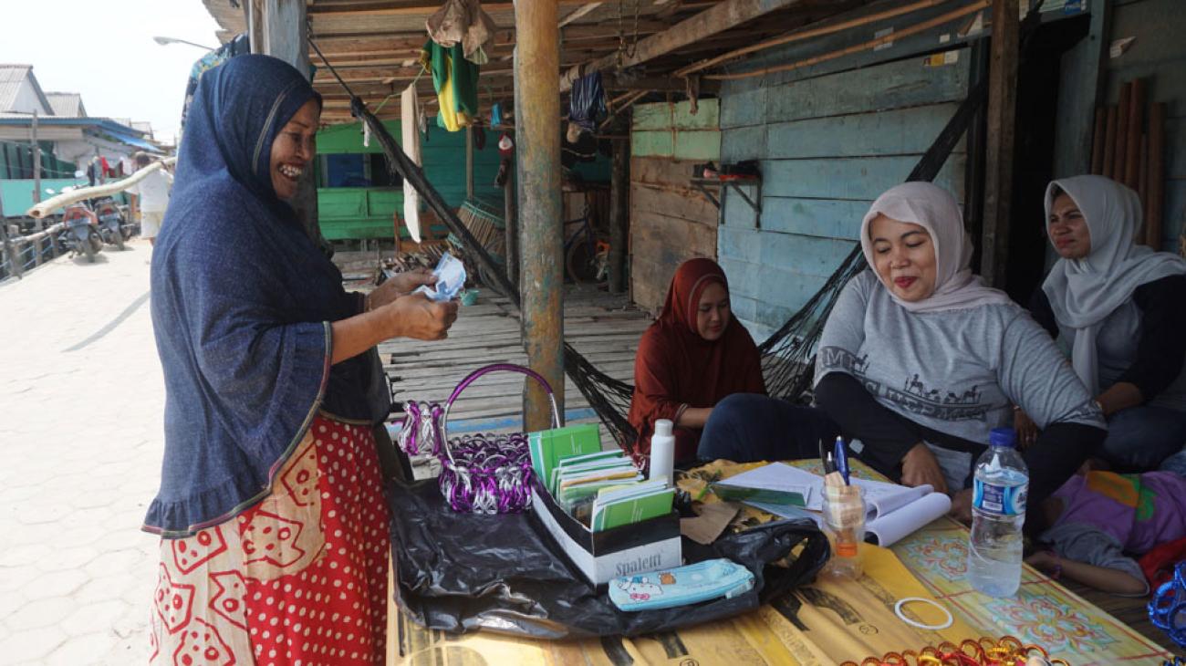 Des femmes portant un voile sur la tête et les épaules discutent sous une devanture en bois.