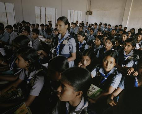 Shows a girl as she stands to answer a question during a class. 