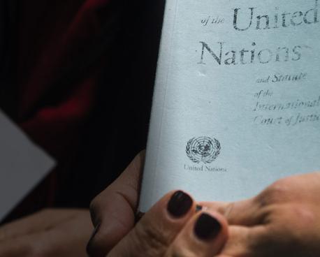 Shows two different hands holding two Charter of the United Nations. 