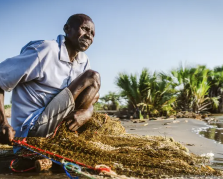 一位非洲男性坐在地上准备捕鱼