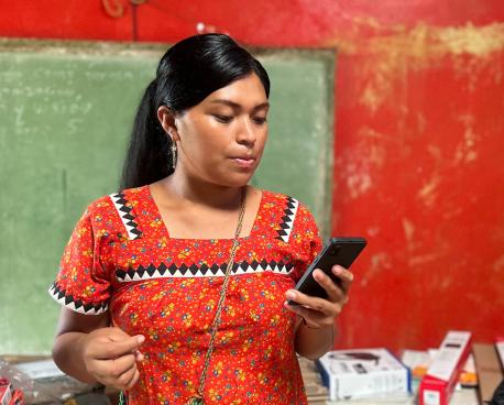 A woman in a bright red dress is looking at her phone.